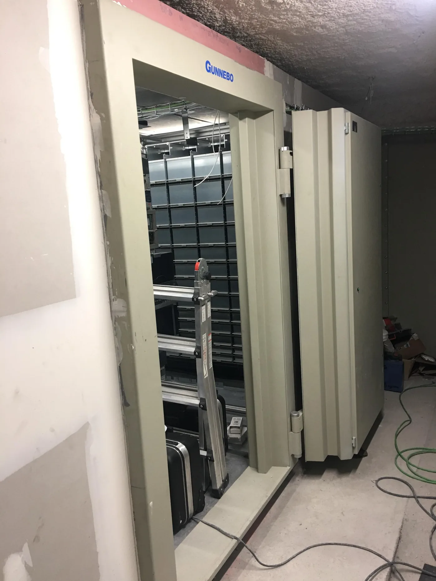 Puerta de cámara acorazada abierta durante la instalación, con los compartimentos detrás.